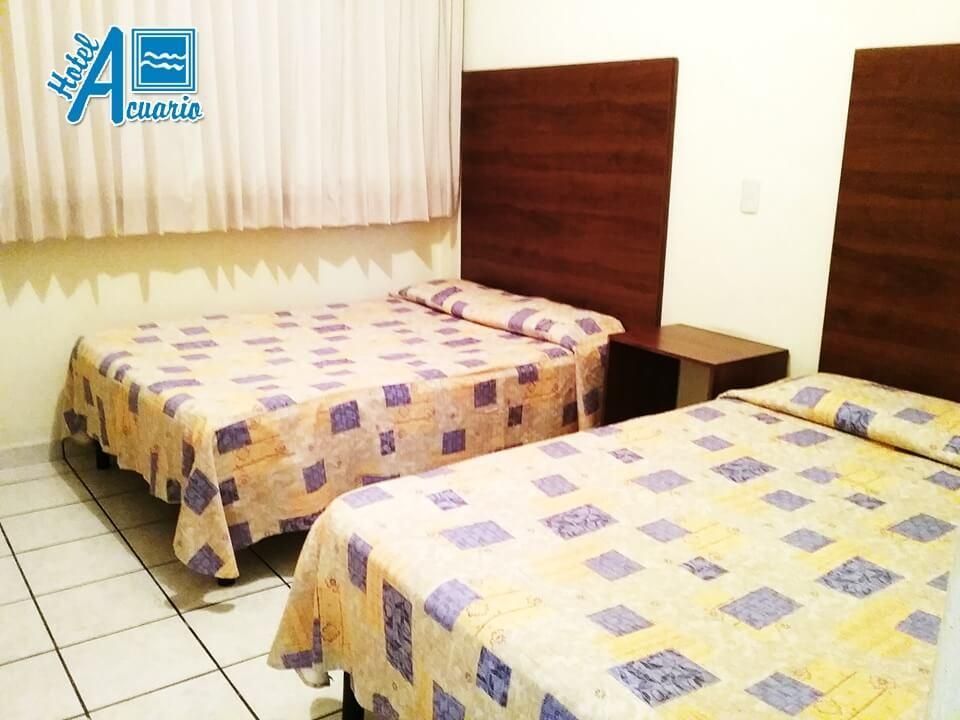 Una habitación de hotel con dos camas y una mesita de noche.