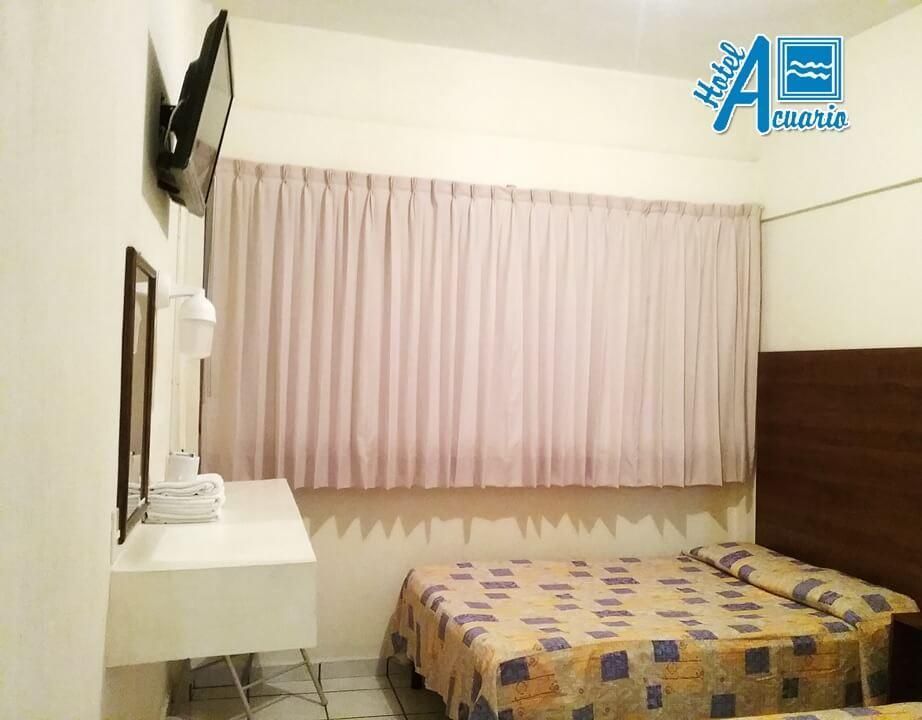 Una habitación de hotel con dos camas y un televisor de pantalla plana.