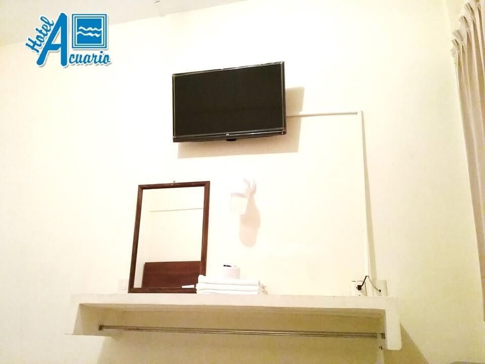 Una habitación de hotel con un televisor de pantalla plana y un espejo.