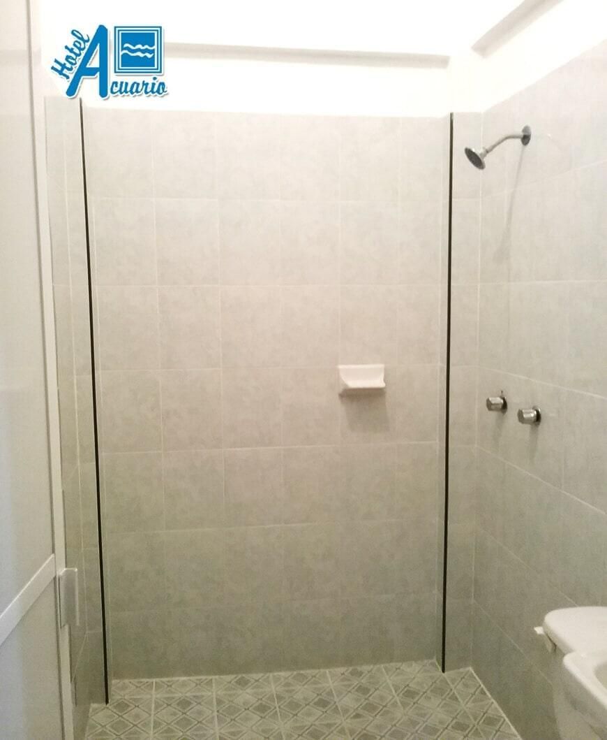 Un baño con ducha a ras de suelo y un inodoro.