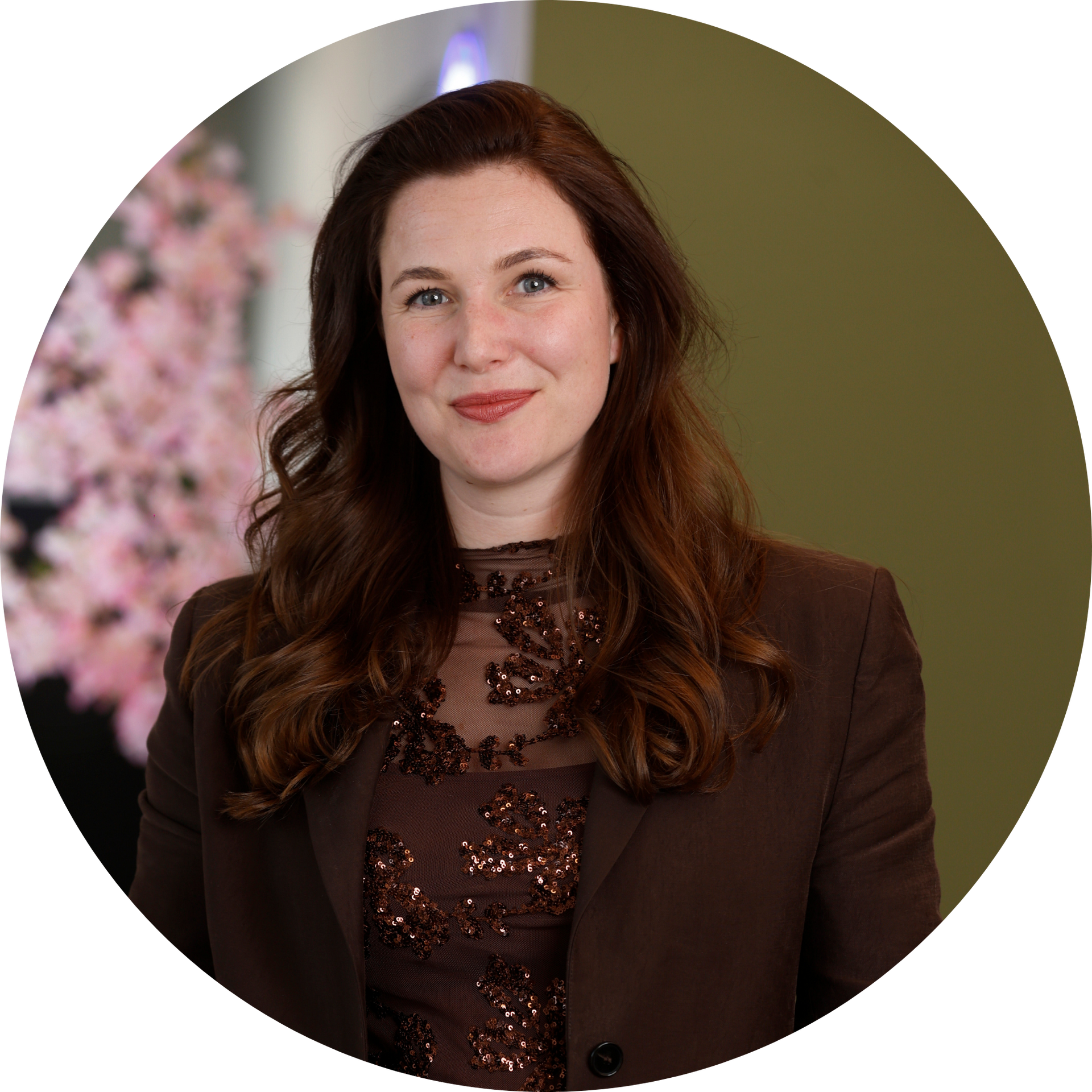 Een vrouw met een bril en oorbellen staat in een veld.