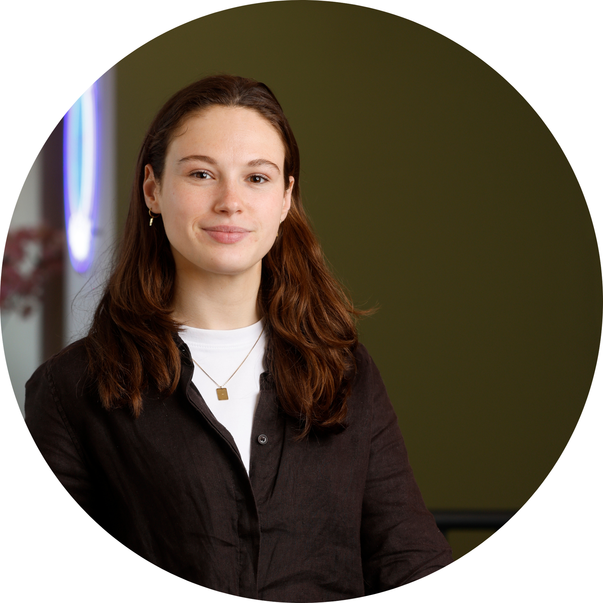 Een vrouw met een bril en oorbellen staat in een veld.