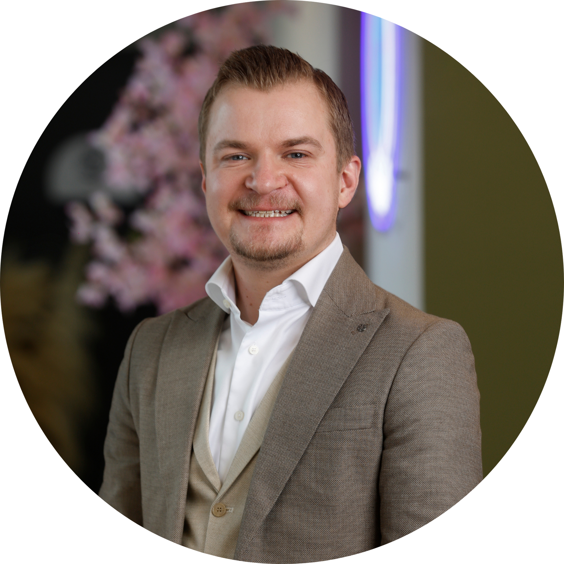 Een kale man in een blauw shirt lacht naar de camera