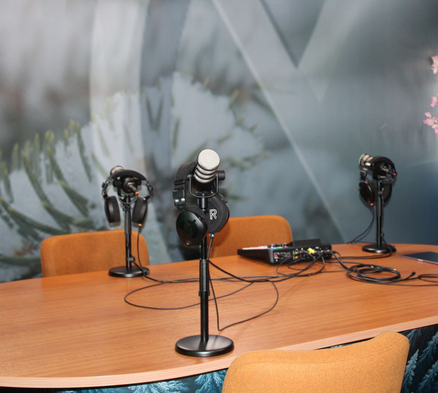 Een tafel met daarop drie microfoons en een koptelefoon