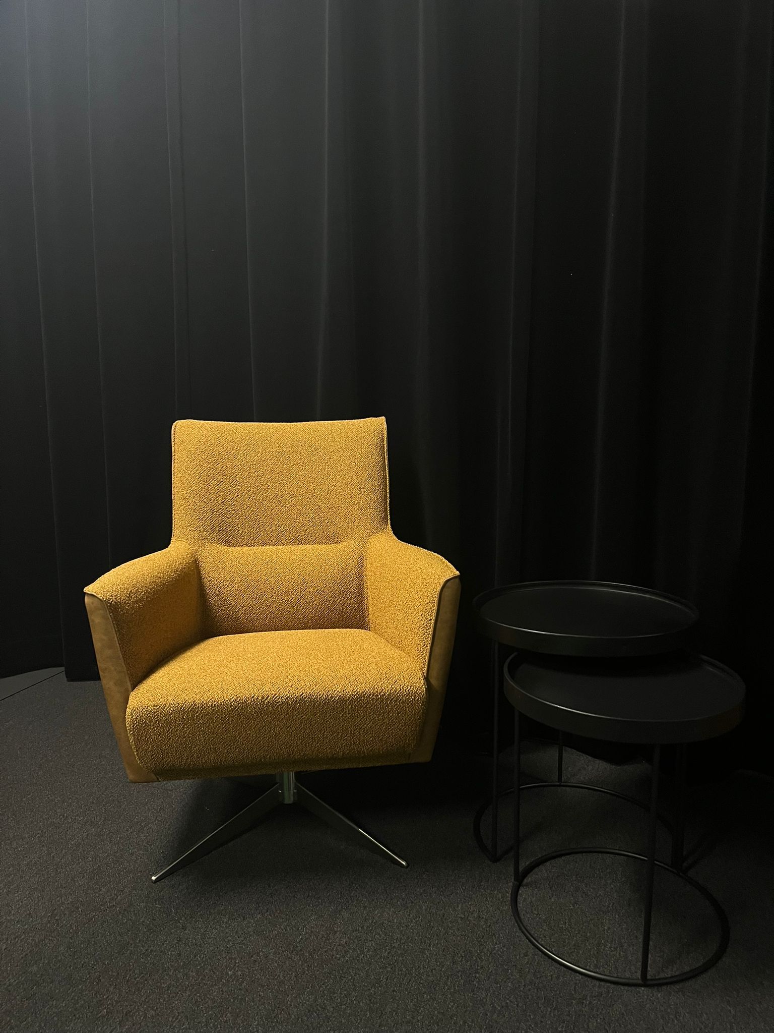 Een gele stoel staat naast een zwarte tafel in een donkere kamer.