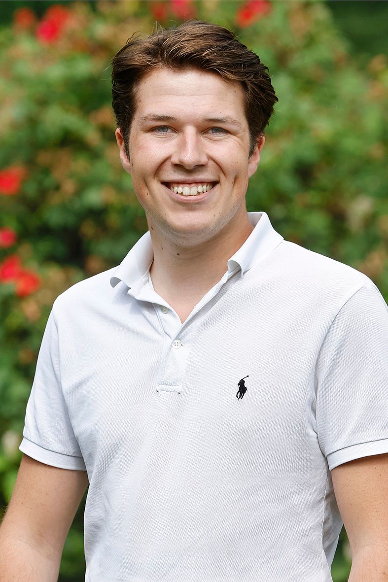 Een man in een wit poloshirt lacht naar de camera