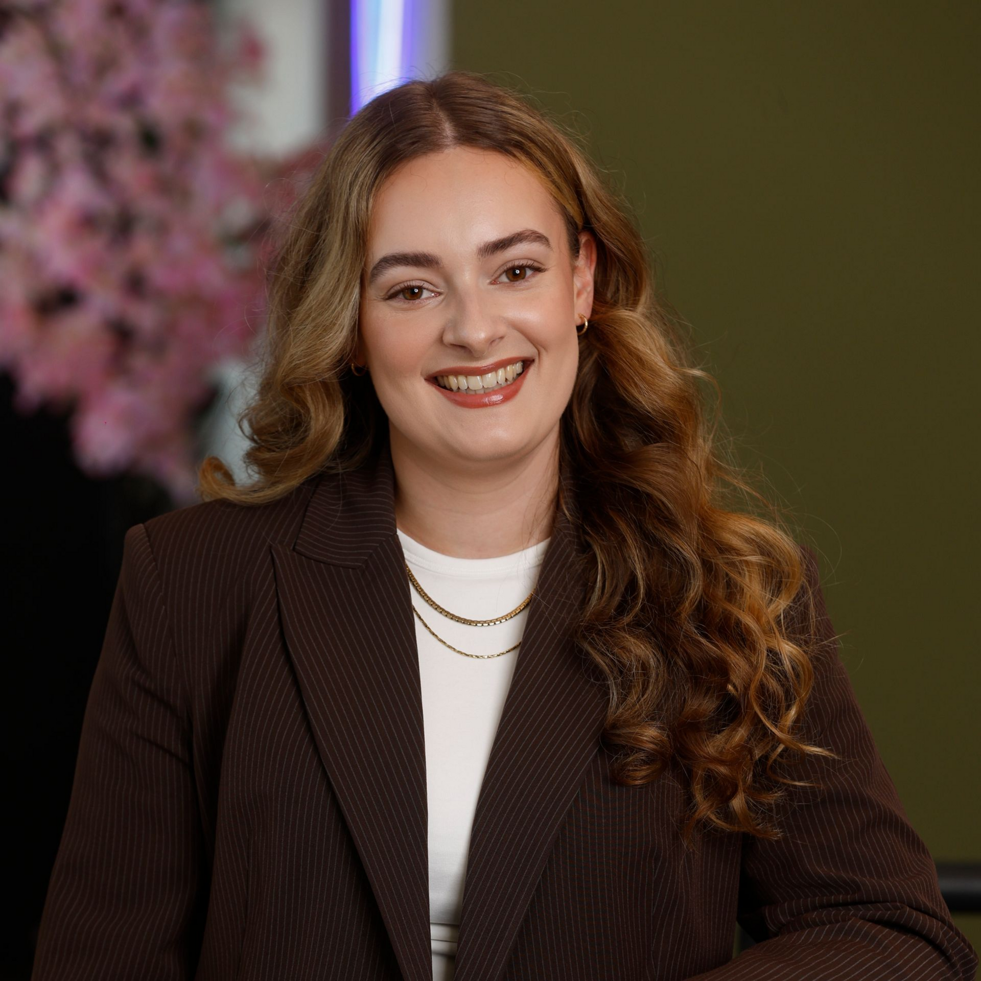 Een vrouw met een bril en oorbellen staat in een veld.