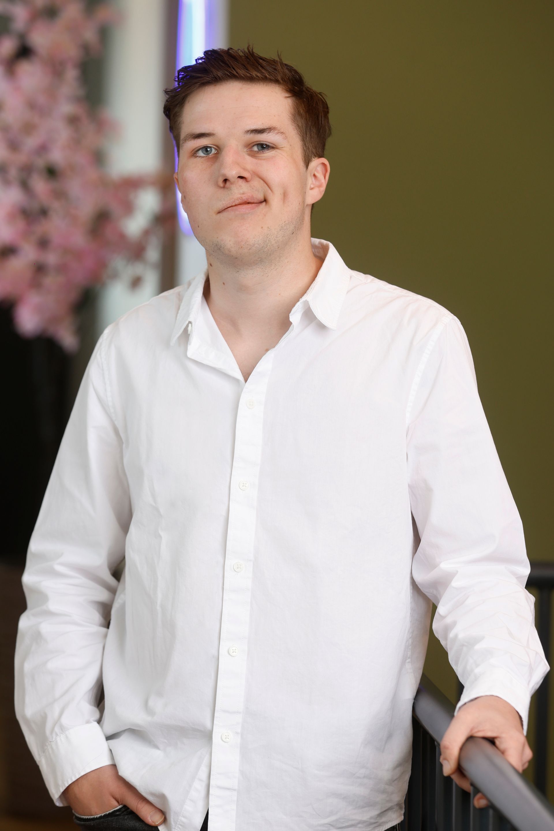 Een man in een wit poloshirt lacht naar de camera