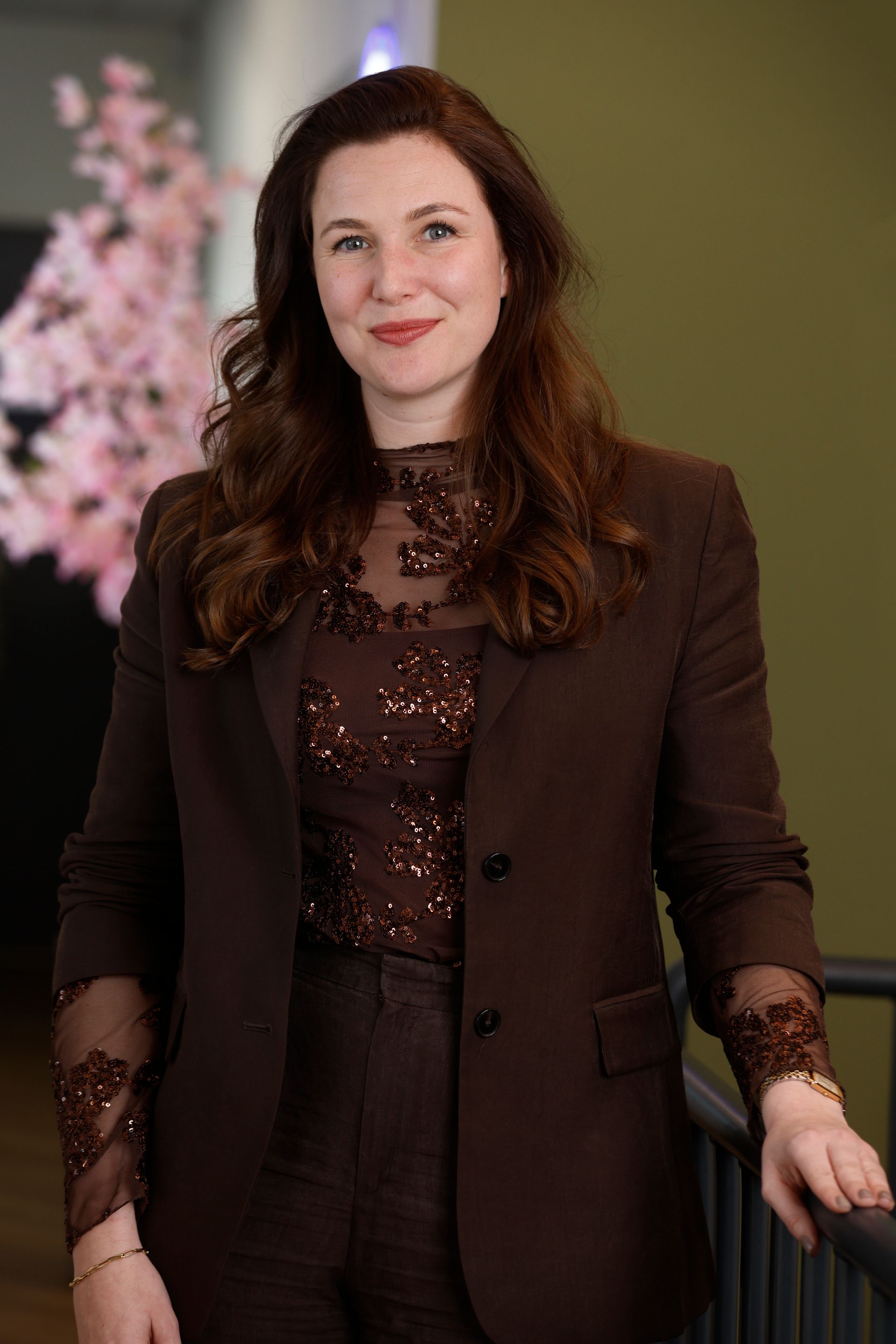 Een vrouw in een blauw gestreept shirt staat voor een struik.