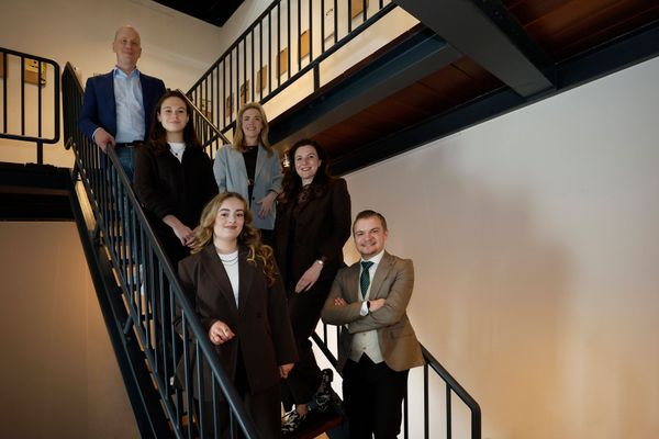 Groep met mannen en vrouwen die in de natuur staan lachend naar de camera
