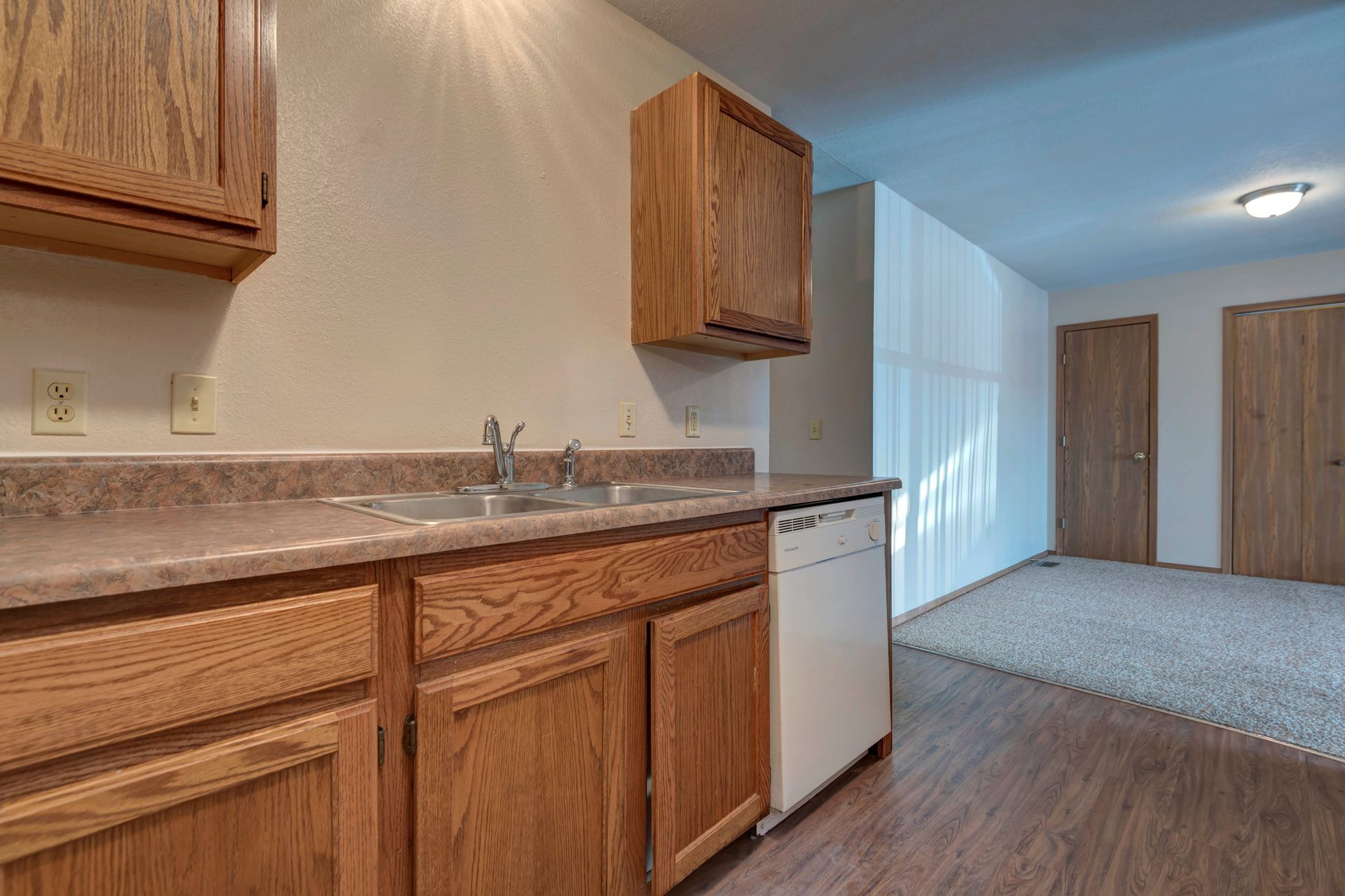 Photo of a long kitchen with the livingroom in the background