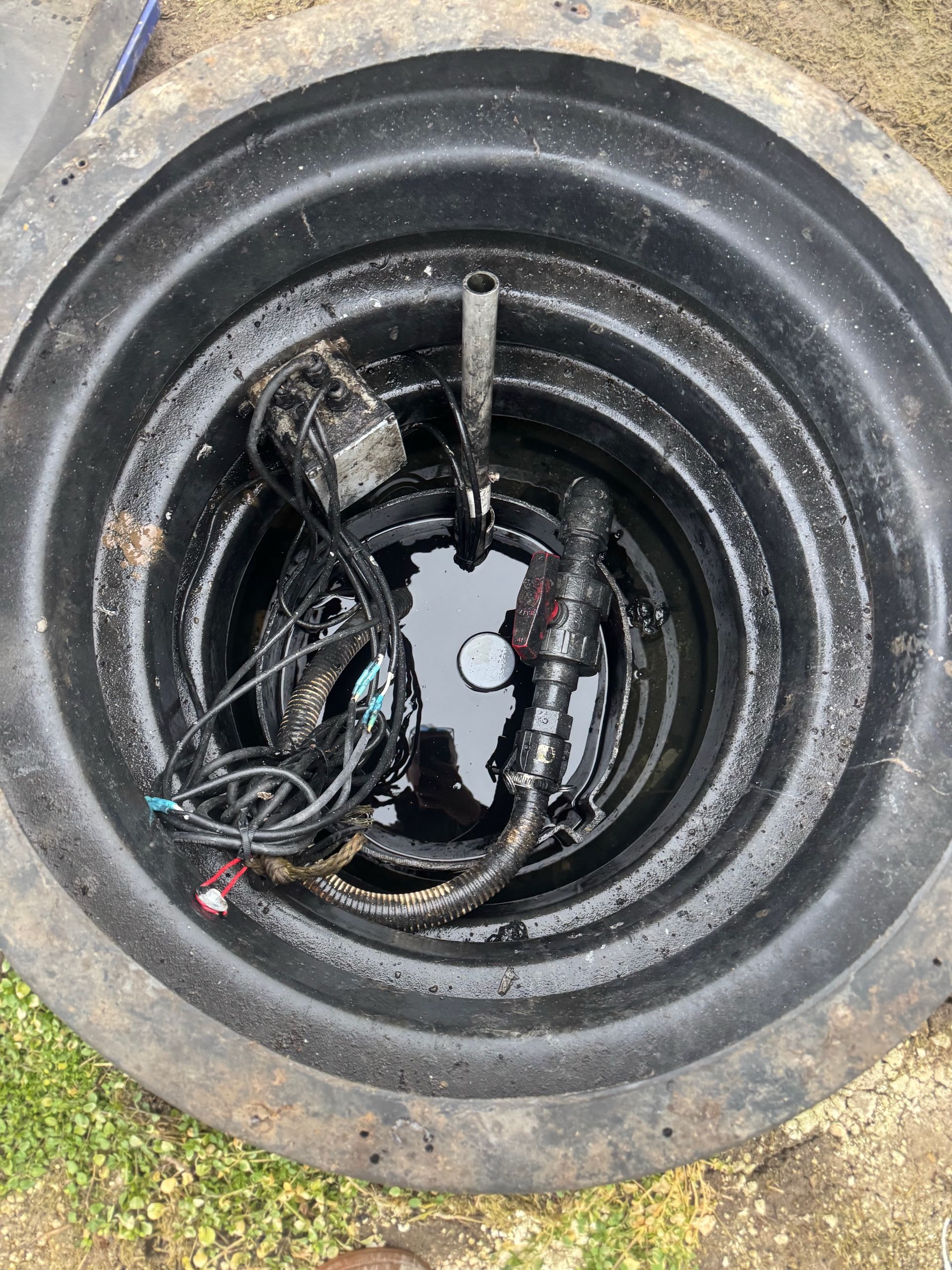 Close-up of a large black tire with tangled cables and debris inside the rim.