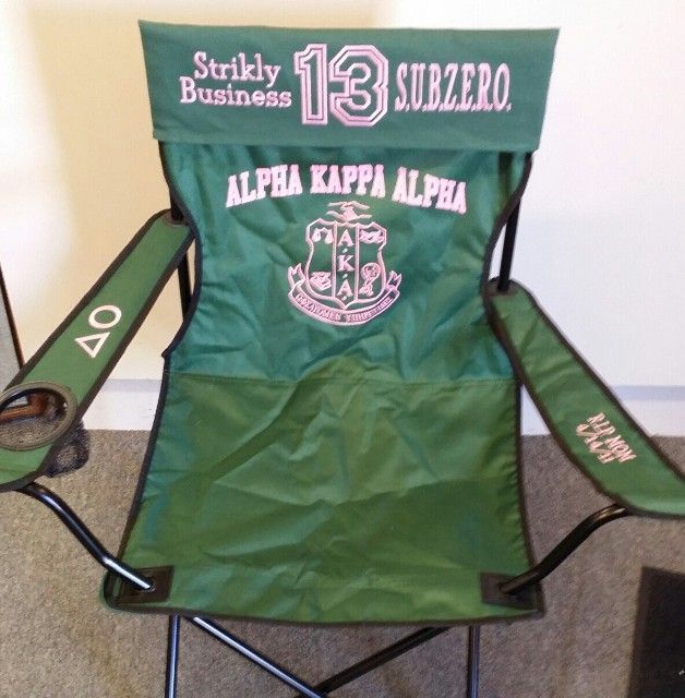 A green folding chair that says alpha kappa alpha on it