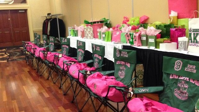 A row of folding chairs with pink duffel bags on them in a room.