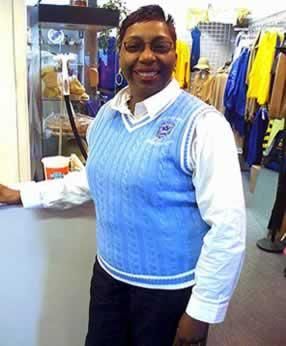 A woman wearing a blue vest and a white shirt is standing in a store.