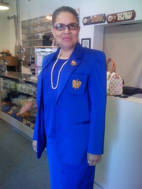 A woman in a blue suit stands in front of a sign that says kru