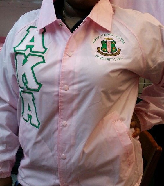 A woman is wearing a pink shirt that says alpha kappa alpha