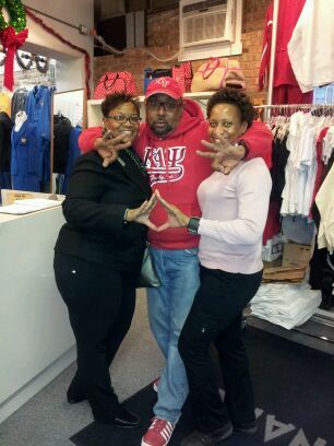 A man wearing a red hoodie that says ' ucsd ' on it poses with two women