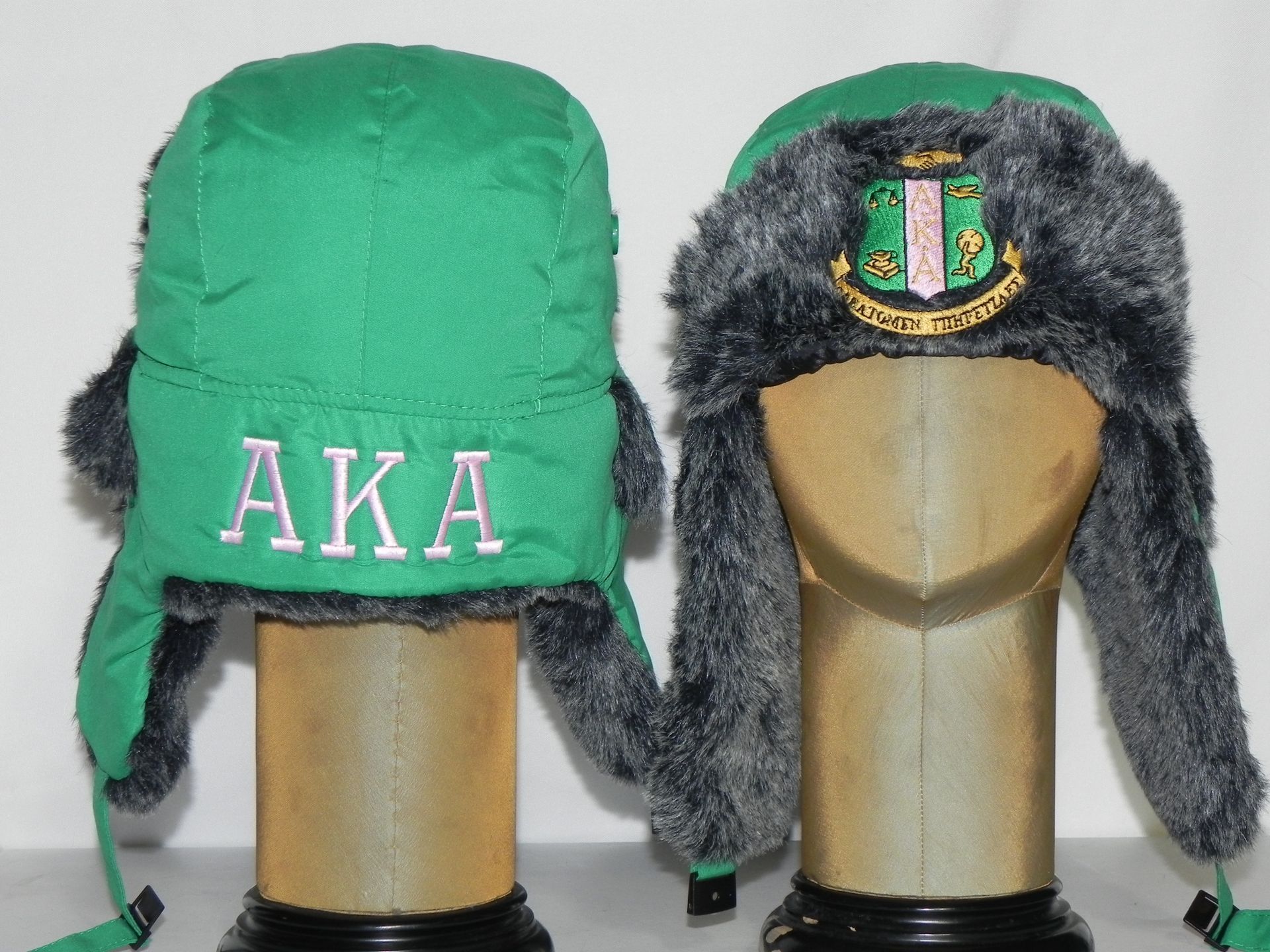 Two green hats with the letters aka on them