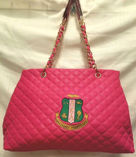 A pink quilted purse with a crest on it