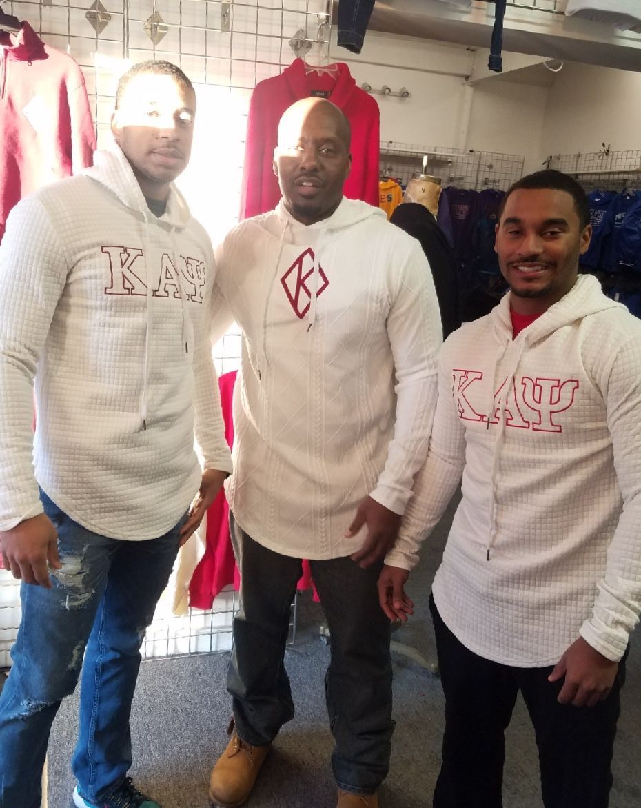 Three men are posing for a picture and one has a kappa hoodie on