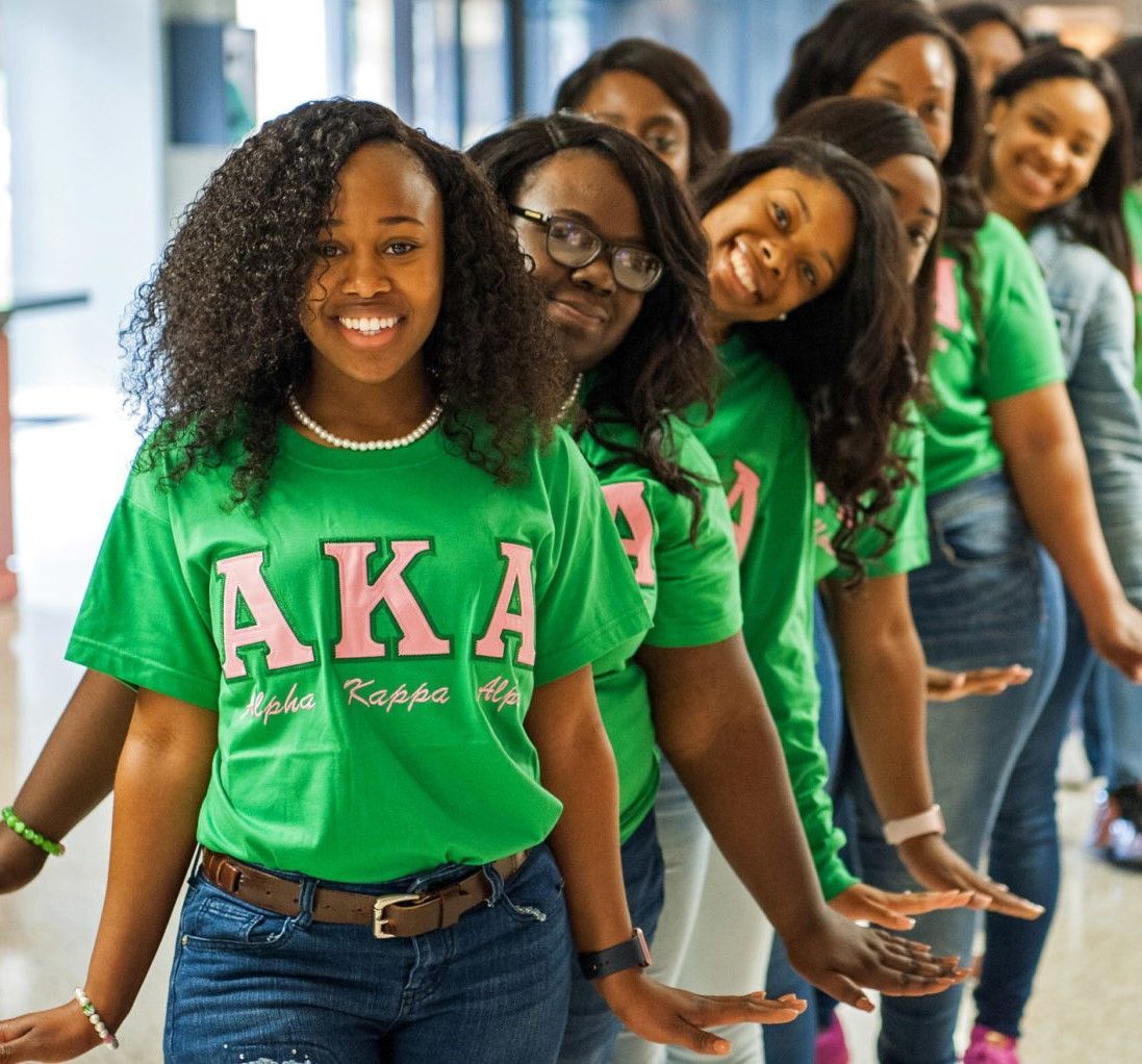 A group of women wearing green aka shirts are standing in a line
