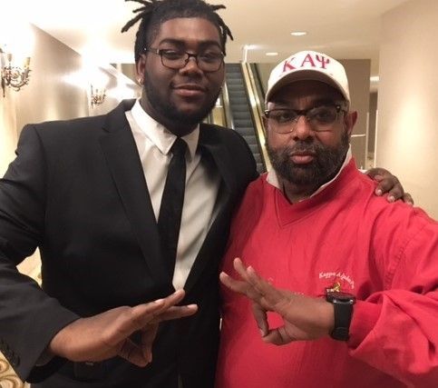 Two men posing for a picture with one wearing a kappa hat