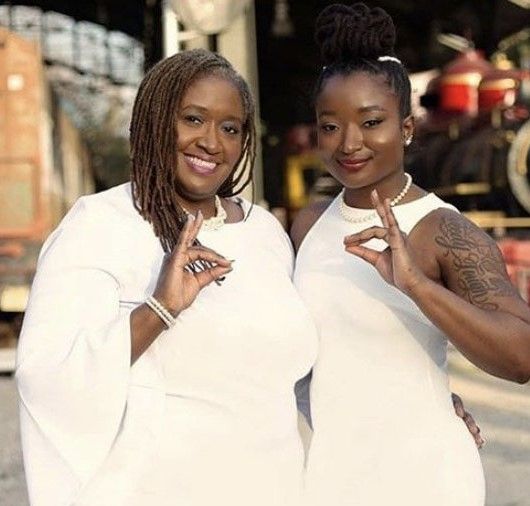 Two women in white dresses are posing for a picture