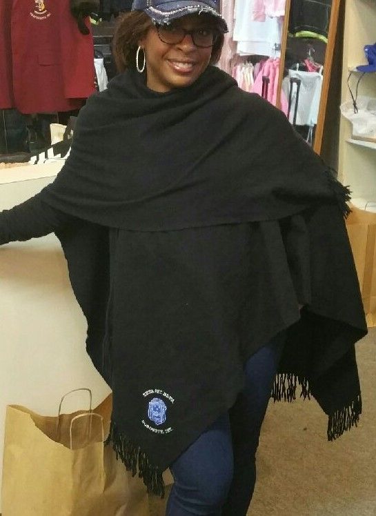 A woman wearing a black poncho with a blue logo on it