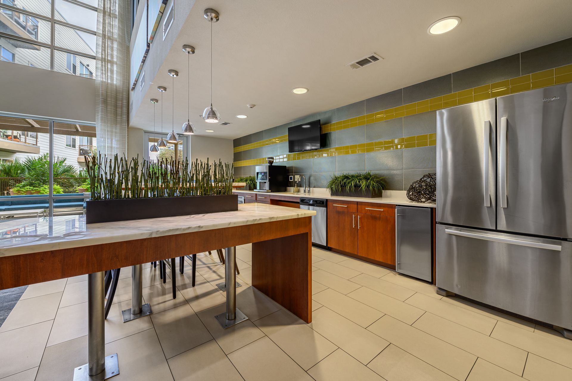 Communal kitchen with large table, stainless steel appliances, and tile backsplash at Sabina, offering apartments near the University of Texas of Austin.