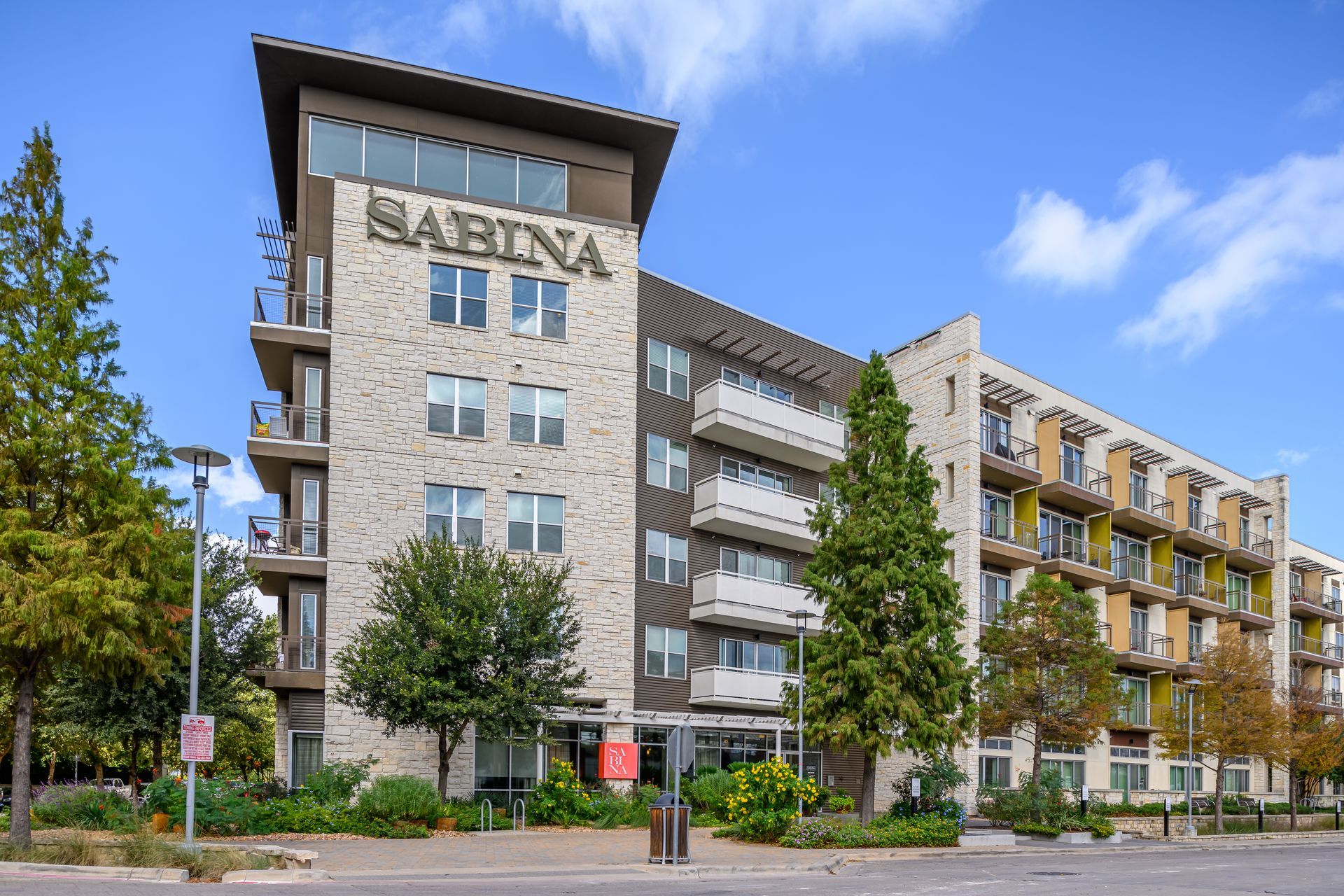 Sabina apartment building with balconies and sign on a sunny day.
