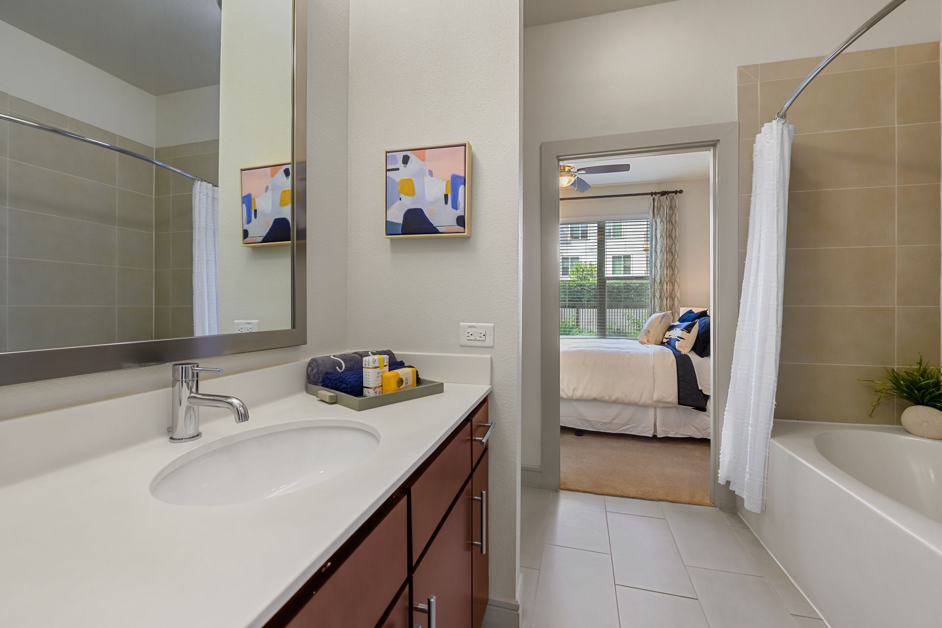 Bathroom with white countertop, brown cabinets, open door to bedroom at Sabina, offering affordable residences in Central Austin, TX.