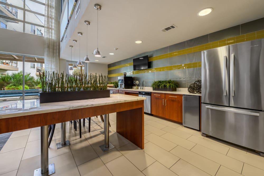 Community kitchen with stainless steel appliances, a table, and a refrigerator at Sabina in Austin, TX.