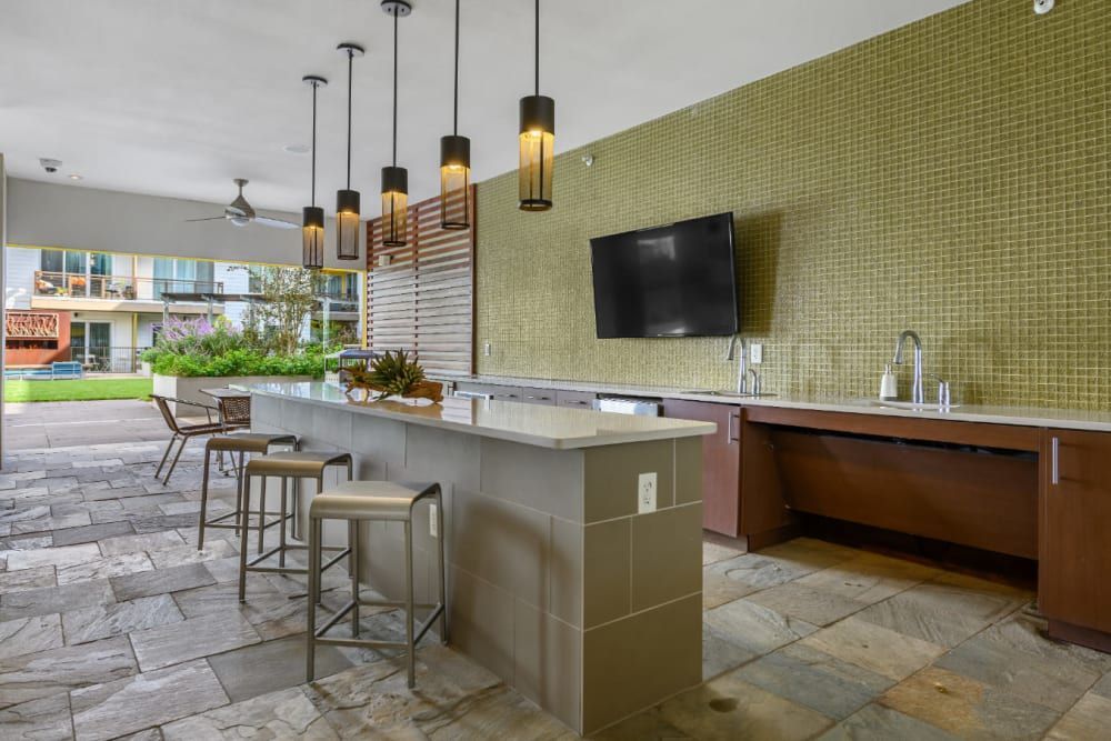 Clubhouse community kitchen with a large island and a flat-screen tv on the wall at Sabina in Austin, TX.