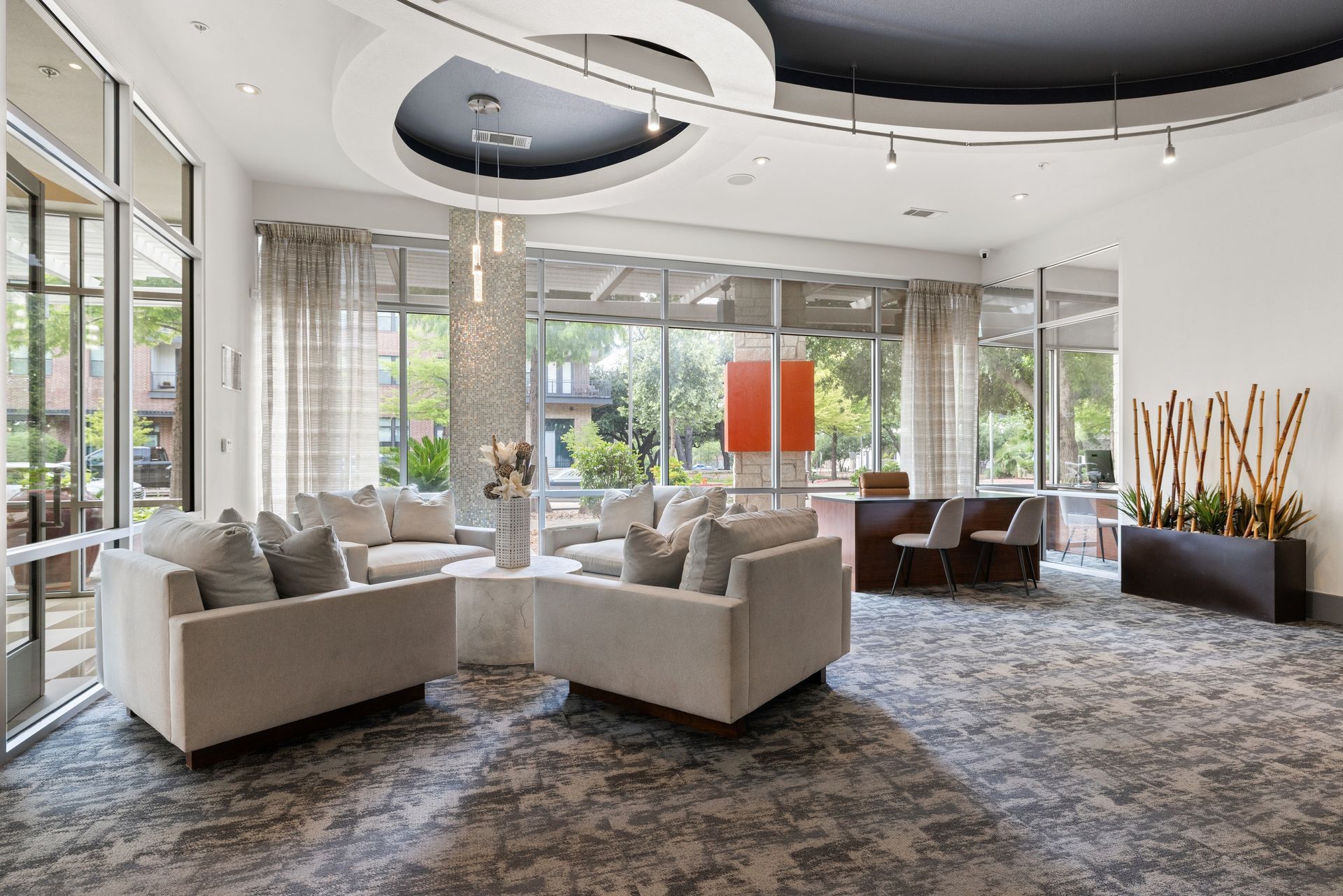 Modern lobby with light sofas, patterned carpet, large windows, and contemporary ceiling lights at Sabina in Austin, TX.