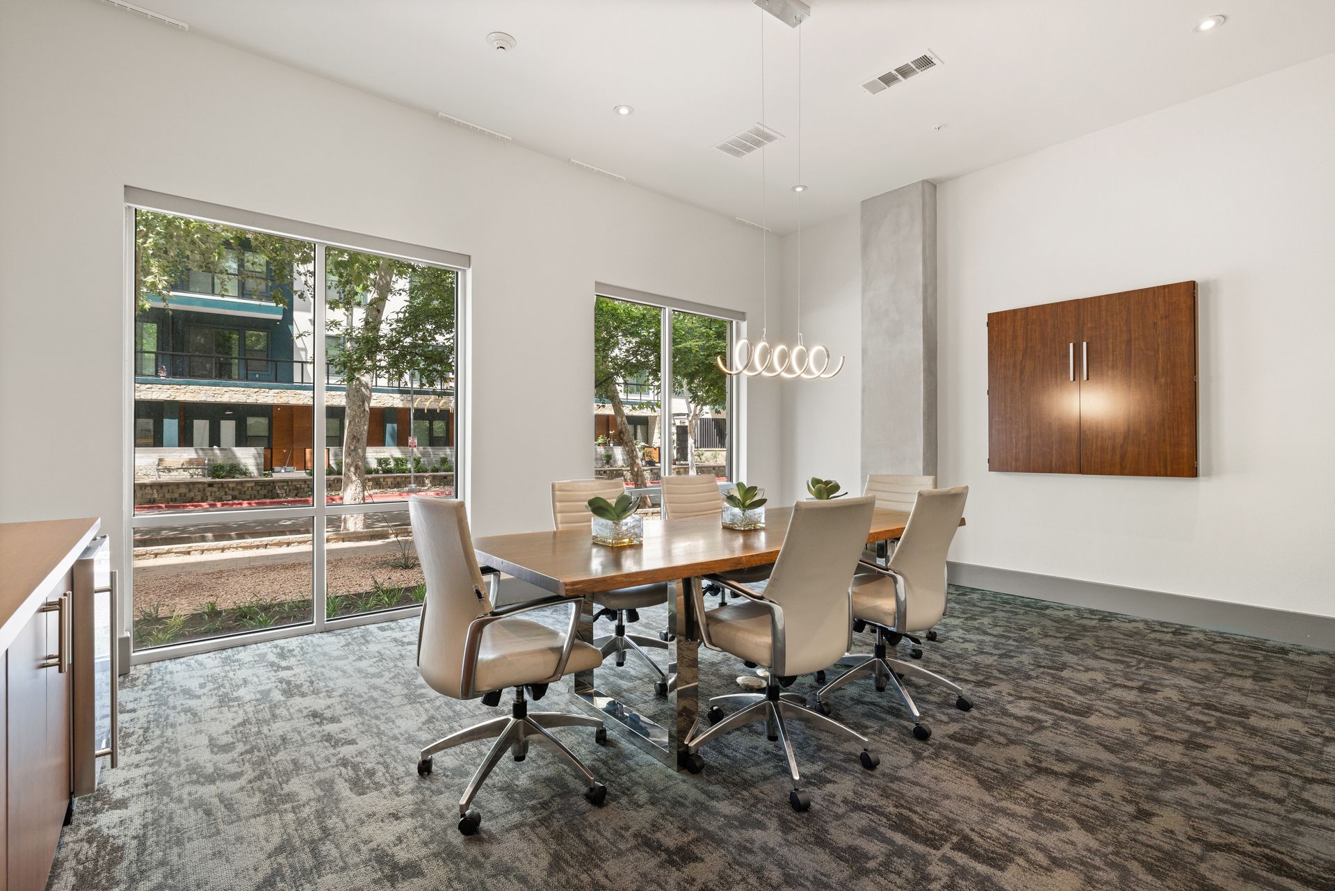 Modern conference room with glass walls, long table, rolling chairs, and wall art at Sabina in Austin, TX.