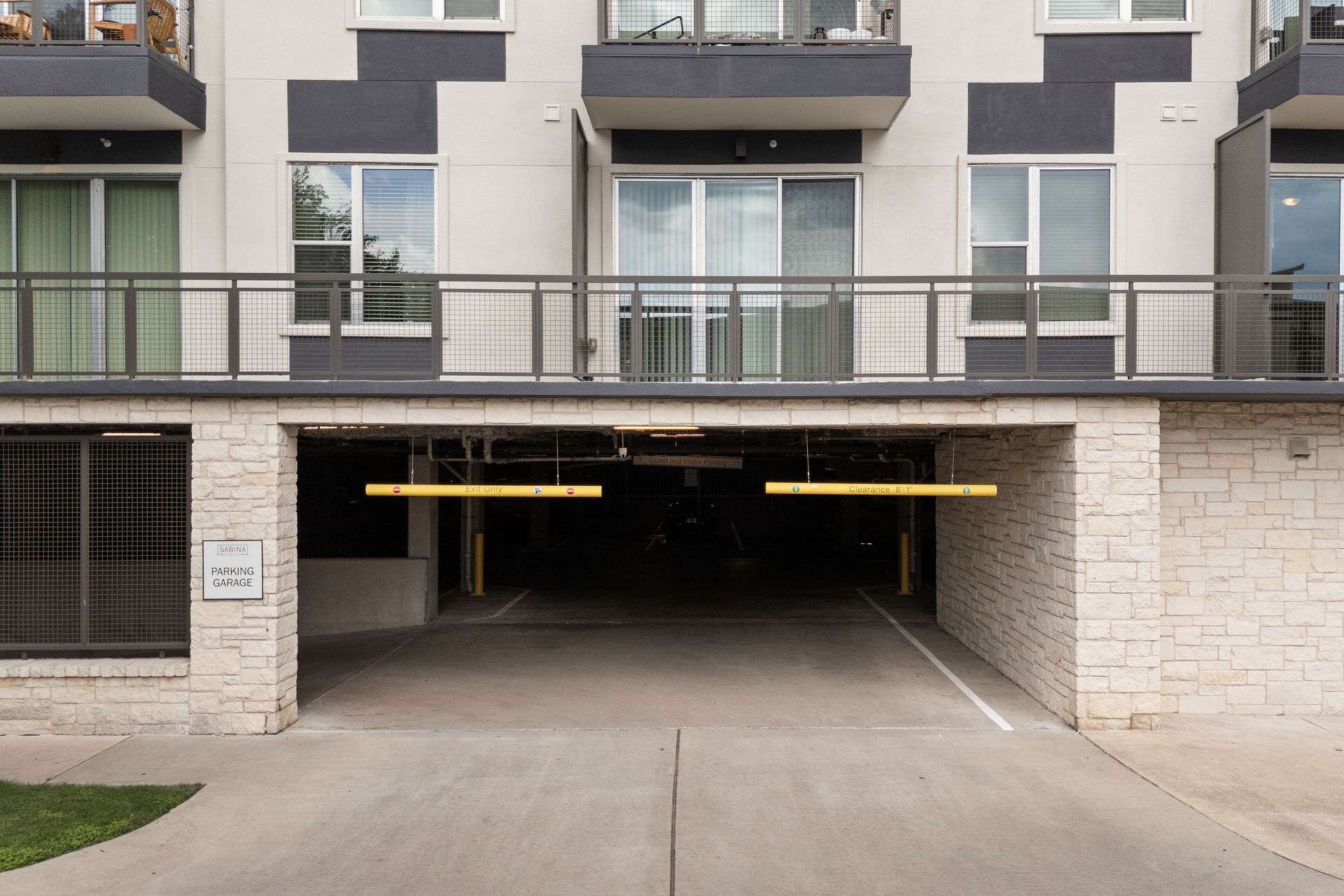Apartment building parking garage entrance with a driveway and overhead lights at Sabina in Austin, TX.