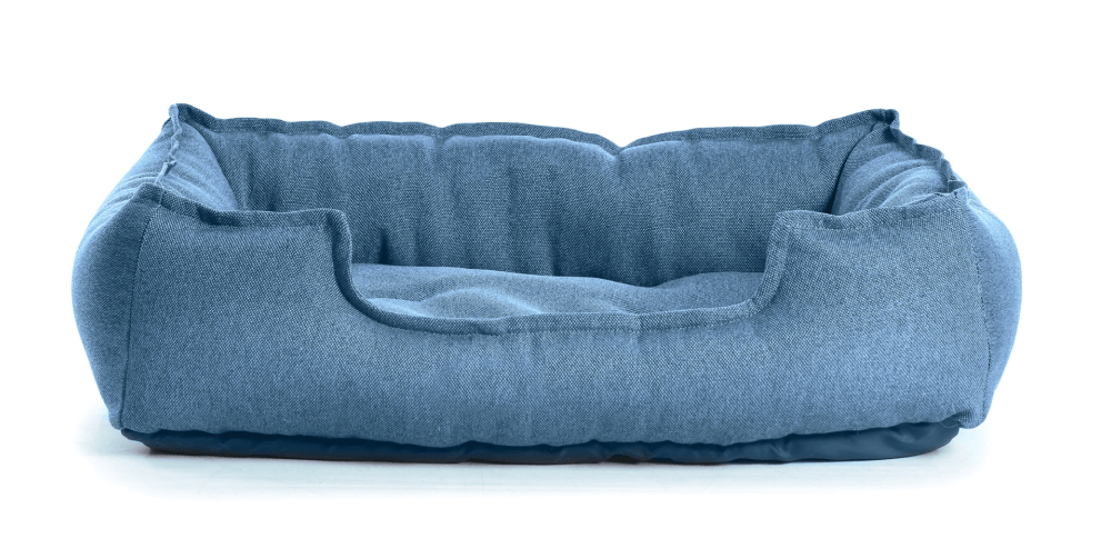 A blue dog bed is sitting on a white surface.