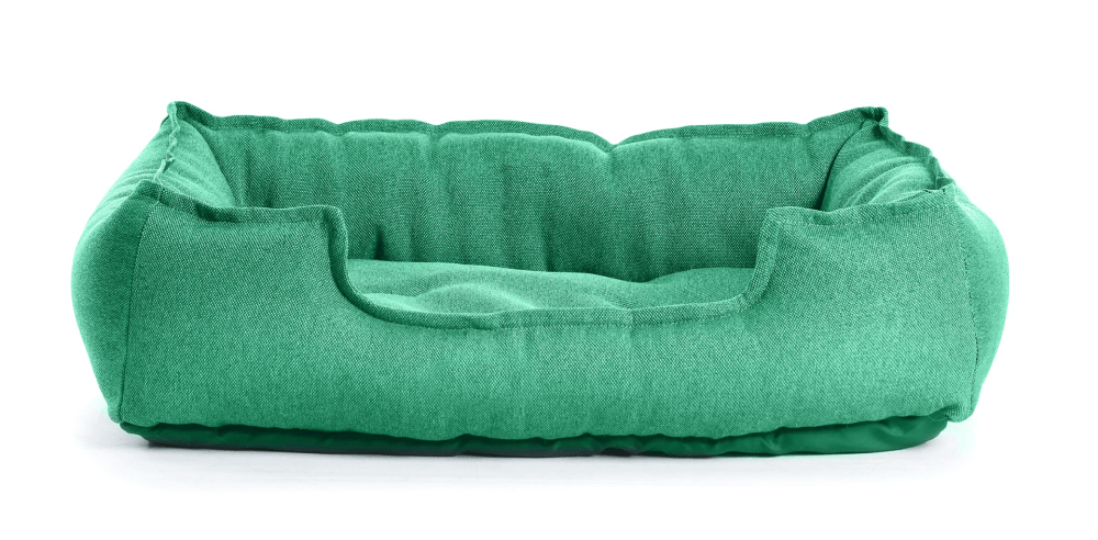 A green dog bed is sitting on a white surface.