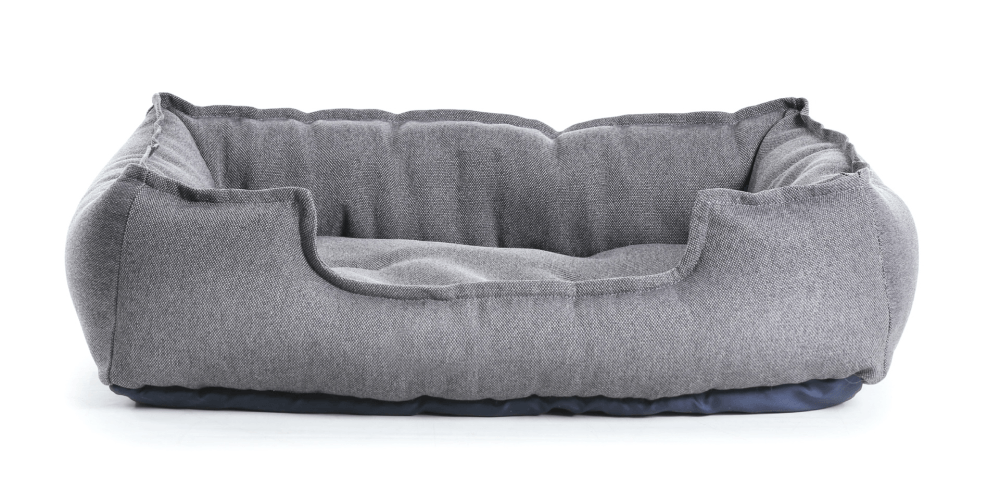A gray dog bed is sitting on a white surface.