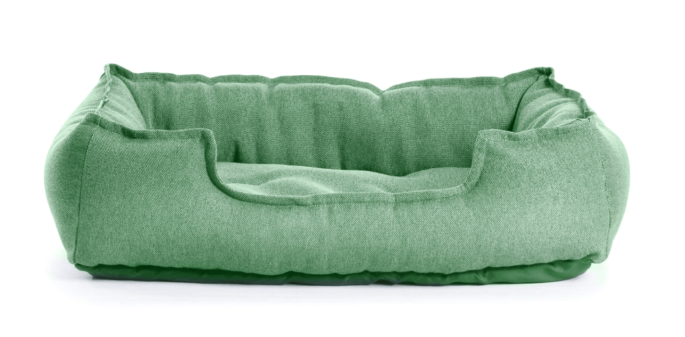 A green dog bed is sitting on a white surface.
