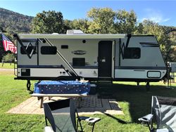 RV parked on grass with table, chairs, and American flag.