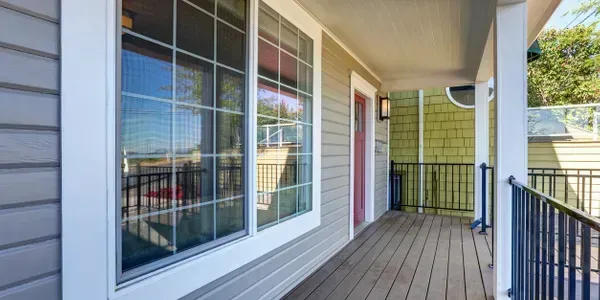 Porch exterior with a large window, gray siding, and a black railing.