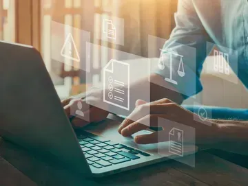 Person using laptop with document icons overlaid.