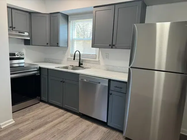 Gray kitchen with stainless steel appliances, white countertops, and gray cabinets.