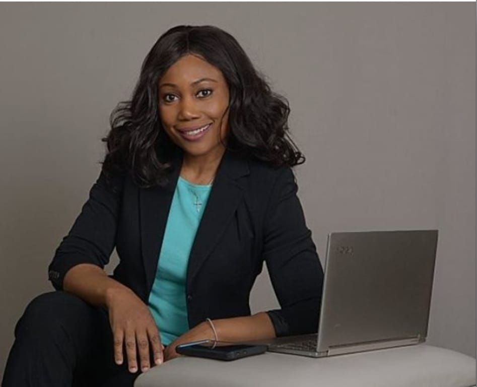 A woman is sitting on the floor in front of a laptop computer.