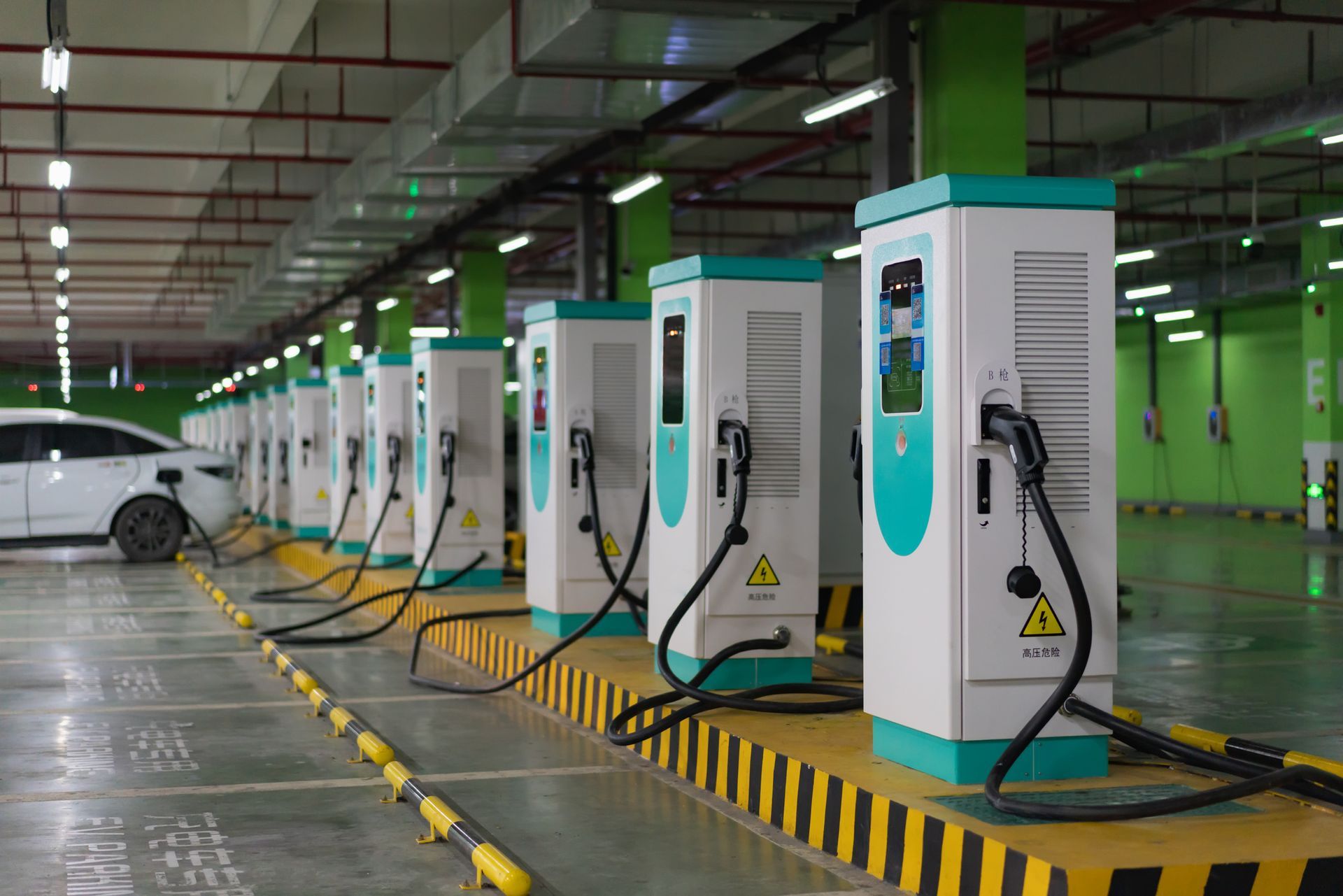 Electric vehicle charging stations in an indoor parking garage with a car charging.