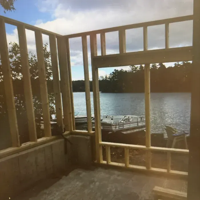 Wooden wall framing for a room addition overlooking a lake, with a large open space framed for a window.