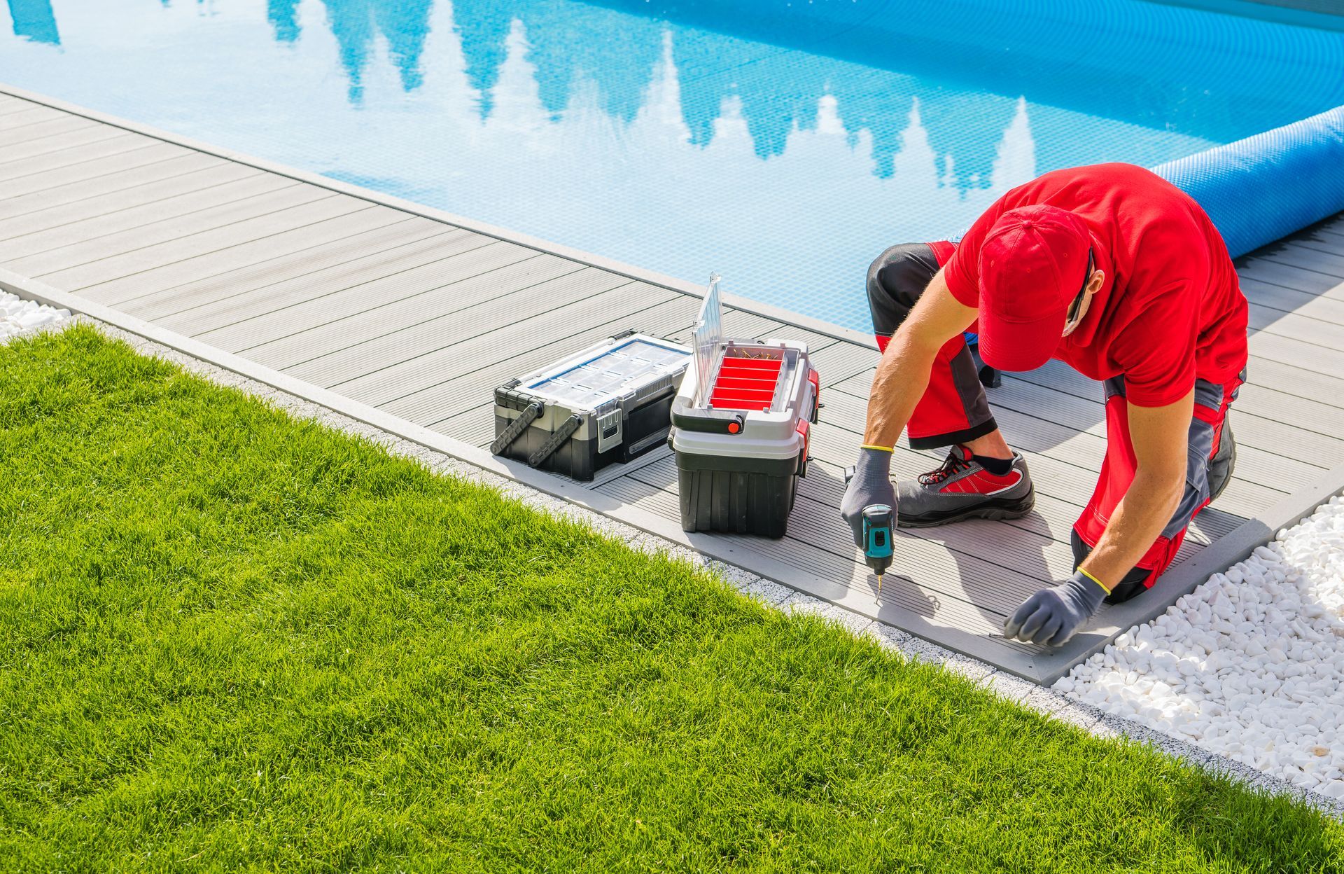 A man is working on the side of a swimming pool.
