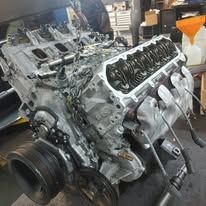 A large engine is sitting on top of a table in a garage.